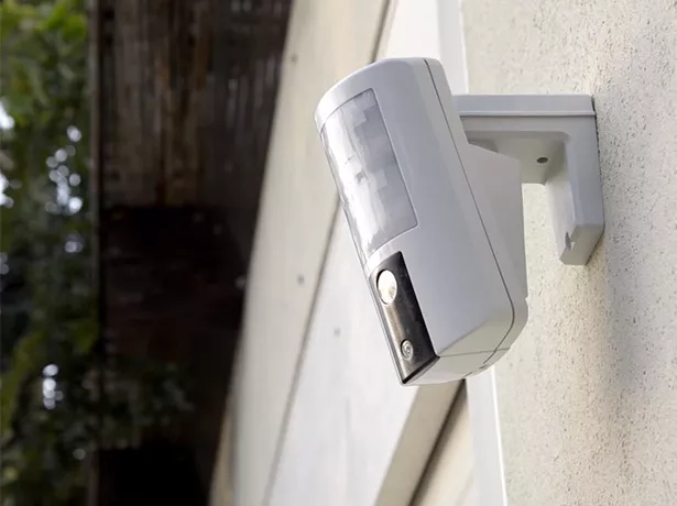 Buitenalarm PIR-detector gemonteerd op buitenmuur voor perimeterbeveiliging rond de woning
